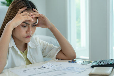 Stressed and headache asian woman with large bills or invoices no money to pay to expenses and credit card debt. shortage, Financial problems, mortgage, loan, bankruptcy, bankruptの写真素材