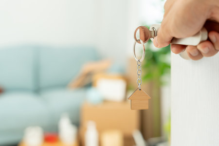 Moving house, relocation. Couple hold key house keychain in new apartment, inside the room was a cardboard box containing personal belongings and furniture. move in new apartmentの写真素材