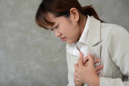 hand hold chest with heart attack symptoms, asian woman working hard have chest pain caused by heart diseaseの写真素材