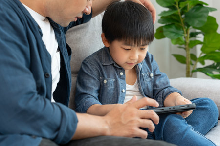 Happy single father playing teach using tablet with the little boy. family is happy and excited in the house. Father and son having spending time together, Good daddyの写真素材