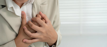 hand hold chest with heart attack symptoms, business woman working hard have chest pain caused by heart disease, press on the chestの写真素材