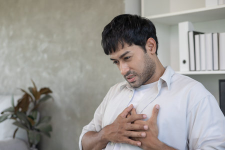 hand hold chest with heart attack symptoms, man working hard have chest pain caused by heart disease, enlarged coronary heartの写真素材
