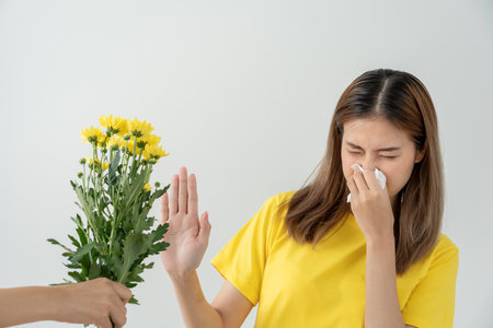 Pollen Allergies, asian young woman sneezing in a handkerchief or blowing in a wipe, allergic to wild spring flowers or blossoms during spring. allergic reactionの写真素材