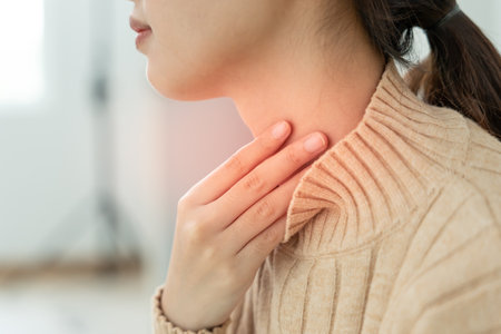 Asian woman with a sore throat. Female tonsillitis causes inflammation. Treated by taking water, antibiotics, and consulting a doctor.の写真素材