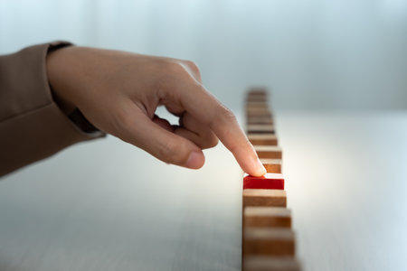 insurance with hands protect domino. Businessman hands stop dominoes falling in business crisis. business risk control and planning and strategies to run preventの写真素材
