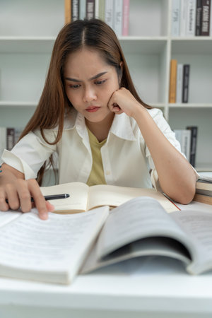 Asian student woman have anxiety because of exams, female prepare for test and learning lessons in the library. stress, despair, haste, misunderstanding reading, discouragedの写真素材