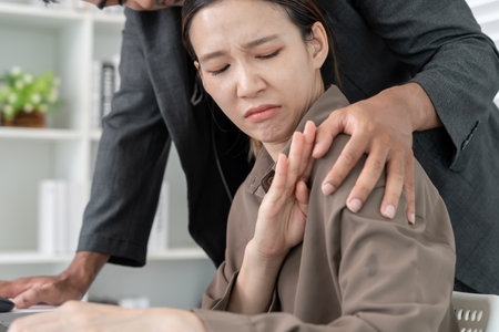 business man sexually harassed a female colleague by touch her shoulder. Sexual harassment in office. Women feel anxious and stressed from being harassed. molest, assaultの写真素材