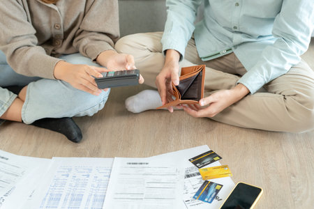 Stressed and headache asian couple with large bills or invoices no money to pay to expenses and...