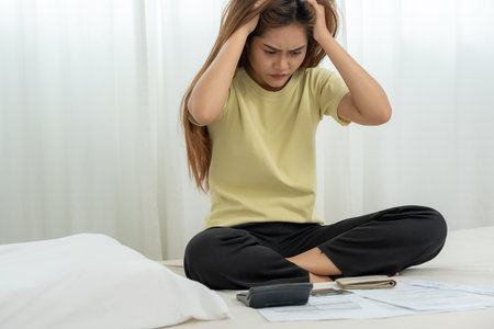Stressed and headache asian woman with large bills or invoices no money to pay to expenses and credit card debt. shortage, Financial problems, mortgage, loan, bankruptcy, bankruptの写真素材