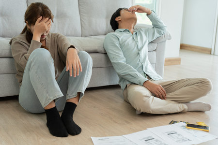 Stressed and headache asian couple with large bills or invoices no money to pay to expenses and...