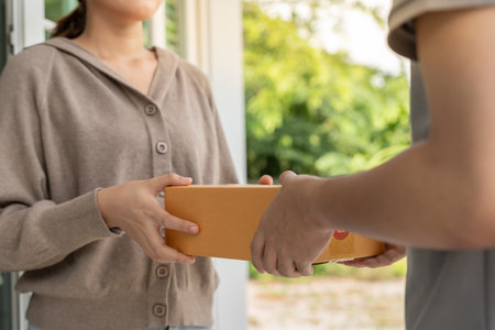 Happy smiling woman receives boxes parcel from courier in front house. Delivery man send deliver express. online shopping, paper containers, takeaway,の写真素材