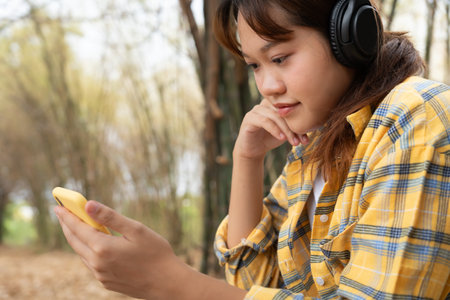 Joyful young Asian women sitting in the garden and enjoy life on holiday, having fun, listening to music, raising his arm, dancing to favorite song, enjoying cool soundtrackの写真素材