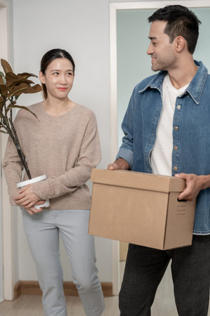 Moving house, Husband and wife hold box and forniture for new apartment or home, inside the room was...