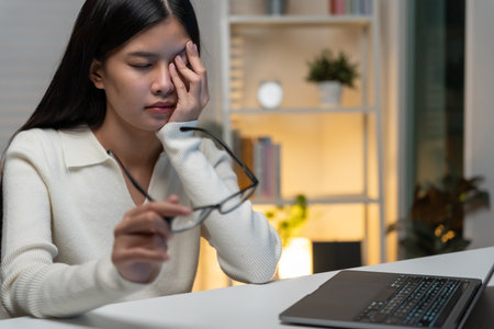 Eye problems, Asian women with tired and irritated eyes, eye rubbing, dry, eye pain after work, migraine, headache, blurred vision, photophobia, working in the dark,の写真素材