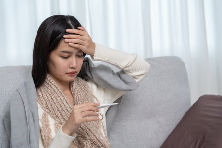 Young Asian woman having high fever while checking body temperature, female sneezing and runny nose...