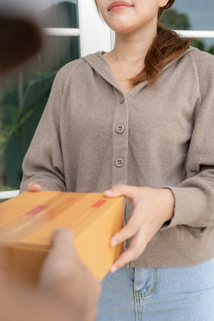 Happy smiling woman receives boxes parcel from courier in front house. Delivery man send deliver express. online shopping, paper containers, takeaway, postman, delivery serviceの写真素材