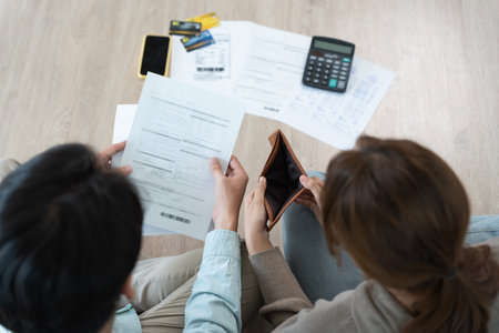 Stressed and headache asian couple with large bills or invoices no money to pay to expenses and credit card debt. shortage, Financial problems, mortgage, loan, bankruptcy,の写真素材