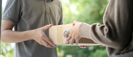 Happy smiling woman receives boxes parcel from courier in front house. Delivery man send deliver...