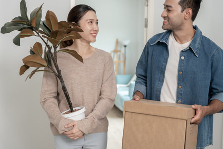 Moving house, relocation. Couples hold carton box contain equipment for new condominium, inside the room was a cardboard box containing personal belongings and furniture.の写真素材