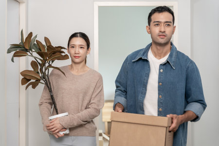 Moving house, Husband and wife hold box and furniture for new apartment or home, inside the room was a cardboard box containing personal belongings and furniture.の写真素材