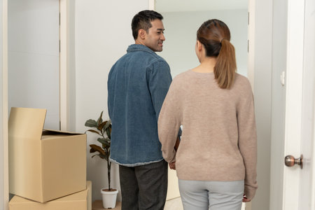 Moving house, relocation. Couple hold hand and open a new house, inside the room was a cardboard box...