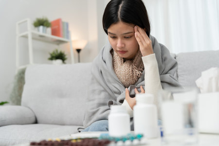 Young Asian woman having high fever while checking body temperature, female sneezing and runny nose with seasonal influenza, taking medicine, virus, coronavirus,の写真素材
