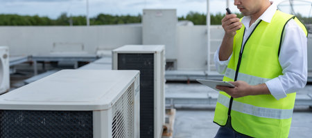 Asian maintenance engineer works on the roof of factory. contractor inspect compressor system and plans installation of air condition systems in construction. technology,の写真素材
