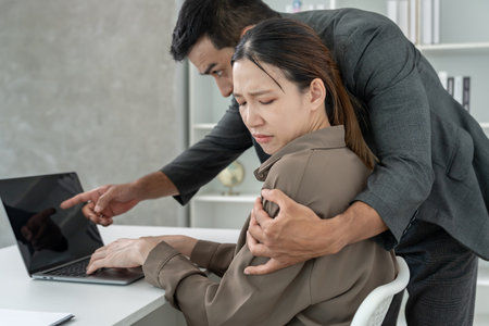 business man sexually harassed a female colleague by touch her shoulder. Sexual harassment in office. Women feel anxious and stressed from being harassed. molest, assaultの写真素材
