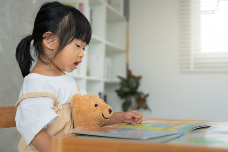 Happy Asian children relax read story book for bear doll. daughter and reading a story. learn development, childcare, education, storytelling, imagine,の写真素材