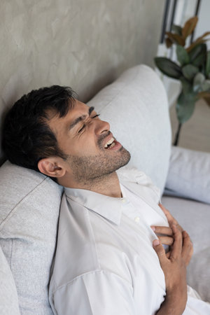 hand hold chest with heart attack symptoms, asian man have chest pain caused by heart disease, leak, dilatation, enlarged coronary heart, press on the chest with a painfulの写真素材