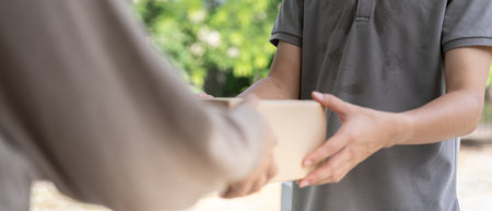 woman receives boxes parcel from courier in front house. Delivery man send deliver express. online shopping, paper containers, takeaway, postman, delivery service, packagesの写真素材
