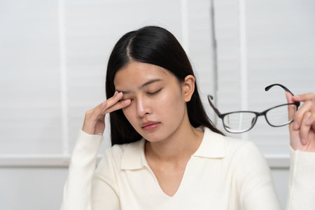 Eye problems, Asian women with tired and irritated eyes, eye rubbing, dry, eye pain after work, migraine, headache, blurred vision, photophobia, working in the dark,の写真素材