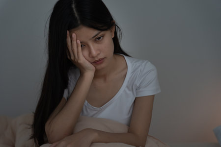 asian woman in bed late trying to sleep suffering insomnia, sleepless or scared in a nightmare, looking sad worried and stressed. Tired and headache or migraineの写真素材