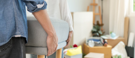 Moving house, relocation. Couple help set sofa and move furniture for new apartment, inside the room was a cardboard box contain personal belongings. move in the new apartmentの写真素材