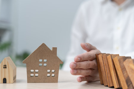 insurance with hands protect domino. Businessman hands stop dominoes falling in house crisis. business risk control and planning and strategies to run prevent insurance businesses.の写真素材