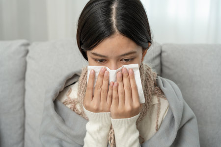 sick woman with a headache sitting under blanket, female sneezing and runny nose with seasonal influenza, allergic, high fever and influenza, resting, virus, coronavirusの写真素材