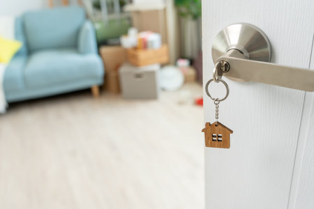 Moving house, relocation. The key was inserted into the door of the new house, inside the room was a cardboard box containing personal belongings and furniture.の写真素材