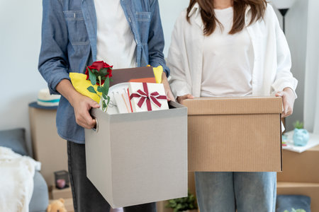 Moving house, relocation. Couple help set sofa and move furniture for new apartment, inside the room was a cardboard box contain personal belongings.の写真素材