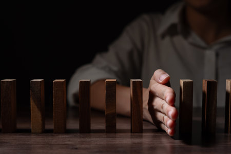 insurance with hands protect domino. Businessman hands stop dominoes falling in business crisis. business risk controlの写真素材