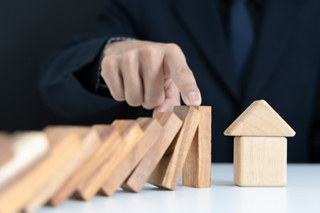 insurance with hands protect domino. Businessman hands stop dominoes falling in house crisis. business risk control and planning and strategies to run prevent insurance businesses.の写真素材