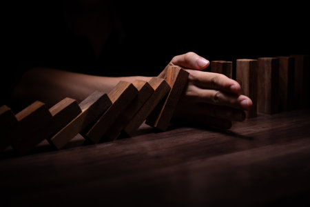 insurance with hands protect domino. Businessman hands stop dominoes falling in business crisis. business risk control and planningの写真素材