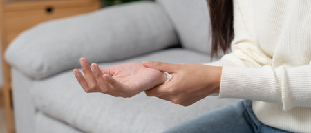 Asian young woman working in office with a carpal tunnel syndrome or wrist joint inflammation, hand muscle inflammation from office syndrome , hand muscle pain from workingの写真素材