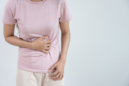 Asian women have stomach ache. Stomach ache due to eating irregularly, menstrual cramps, flatulence, diarrhea, bloating, bloating, abdominal inflammation, food poisoningの写真素材