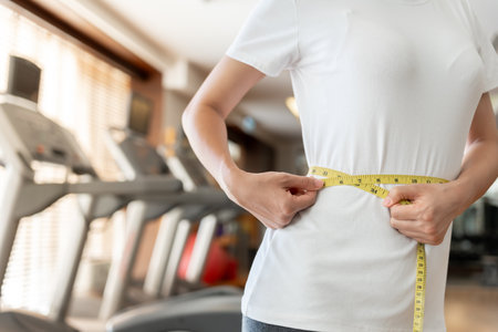 Diet and dieting. Beauty slim female body use tape measure on fitness. Woman in exercise clothes achieves weight loss goal for healthy life,の写真素材