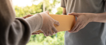 Happy smiling woman receives boxes parcel from courier in front house. Delivery man send deliver...