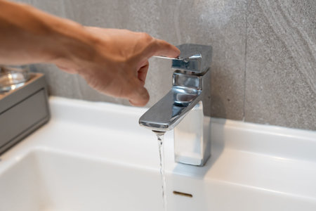 Save water. Man keeps turning off the running water in the bathroom to protect environment.