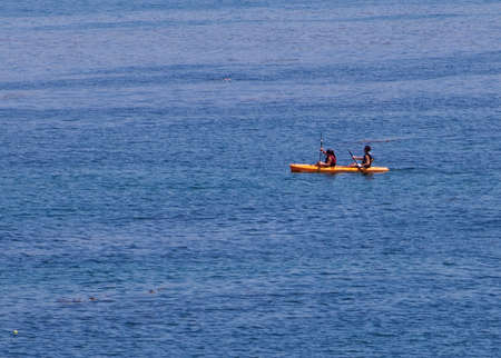 two people cannoeing in the open ocean. lots of open space for text
