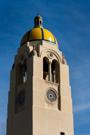 church bell tower with yellow and blue tile on the top. blue sky background.の写真素材