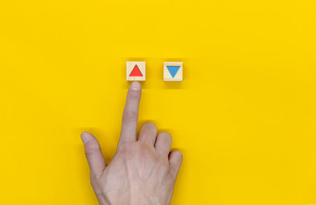 The hand that selects the up out of the wooden blocks marked with the up and down iconの写真素材