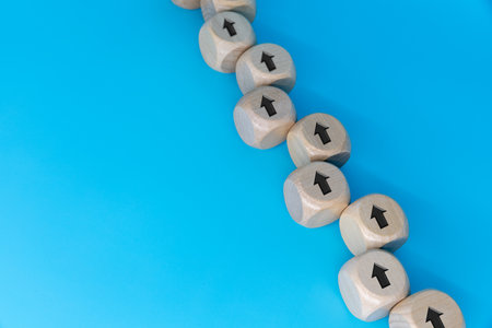 Businessman's manual work of stacking wooden blocks like arrow-facing stairs, concept of business growth success processの写真素材